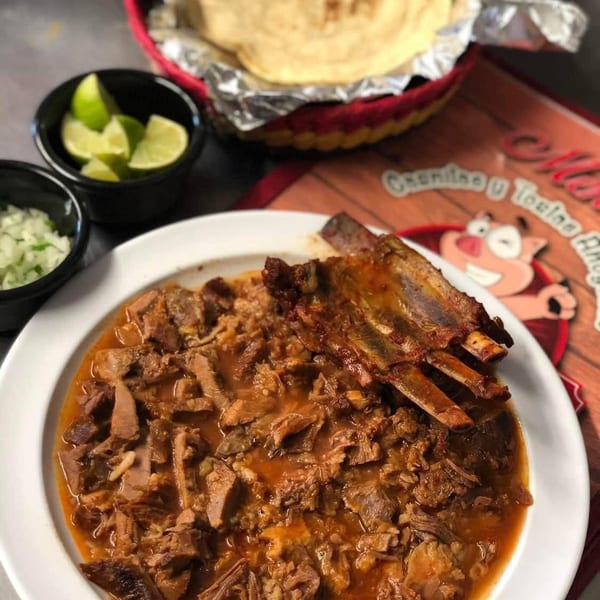 Hearty stew with meat and ribs, served with tortillas, limes, and onions.
